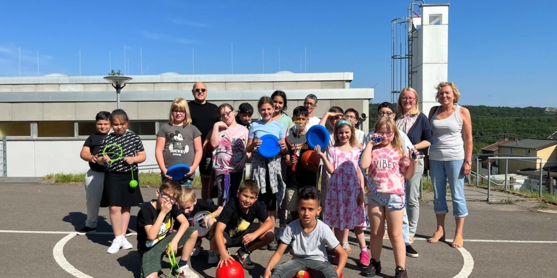 Tanja Schepp, Schulleiterin der Hofschule Bildstock, freut sich mit den Kindern über die gespendeten Spiele.