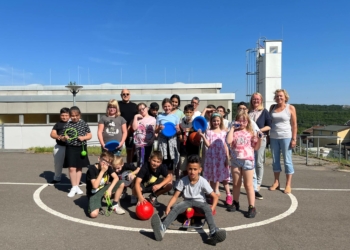 Tanja Schepp, Schulleiterin der Hofschule Bildstock, freut sich mit den Kindern über die gespendeten Spiele.