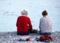 Alte und junge Frau sitzen am Strand