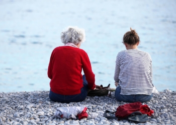 Alte und junge Frau sitzen am Strand