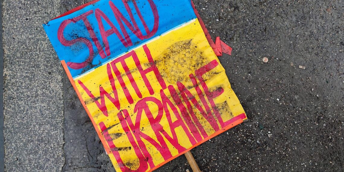 Schild `Stand with Ukraine` liegt auf dem Boden (Archiv)