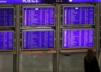 Frau vor Informationstafel am Frankfurter Flughafen
