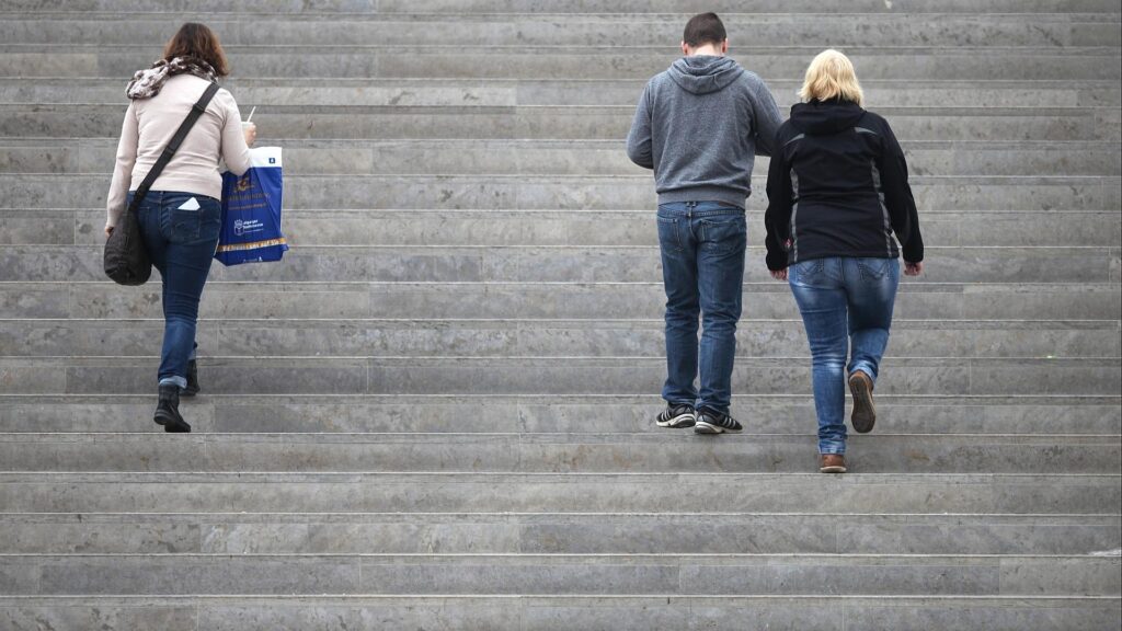 Drei Personen gehen eine Treppe hinauf (Archiv)