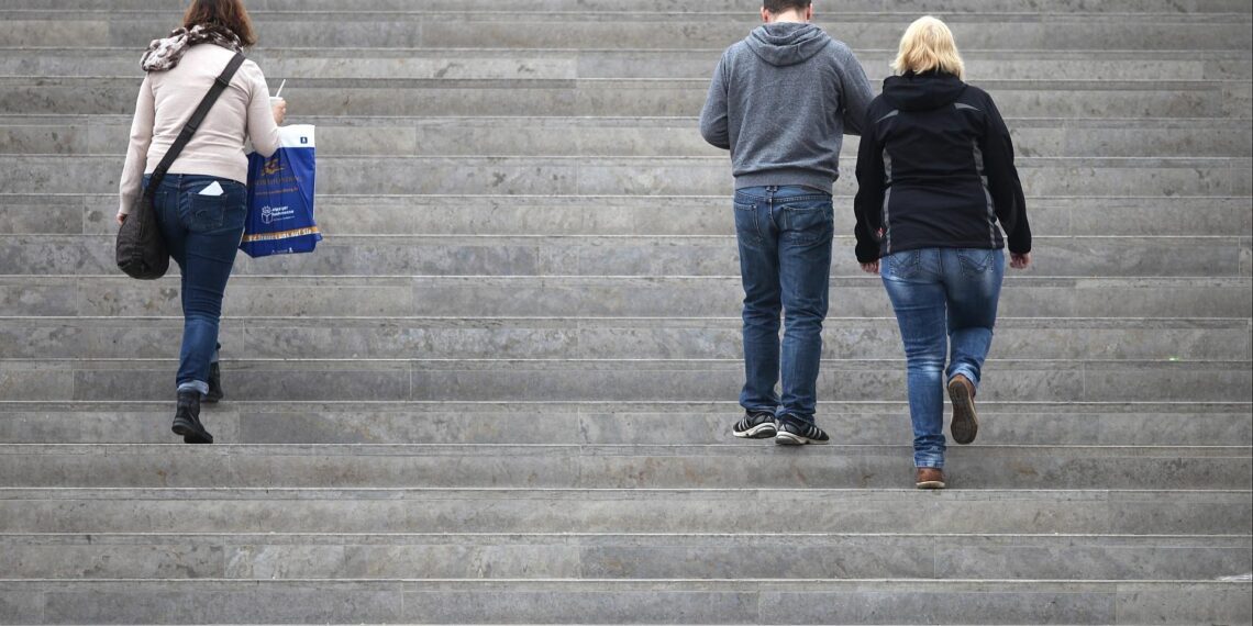 Drei Personen gehen eine Treppe hinauf (Archiv)