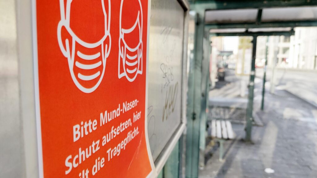 Masken-Affäre: Grüne fordern Aufklärung von Merz mit 90 Fragen 3 Hinweis auf Mund-Nasen-Schutz an einer Straßenbahnhaltestelle (Archiv)