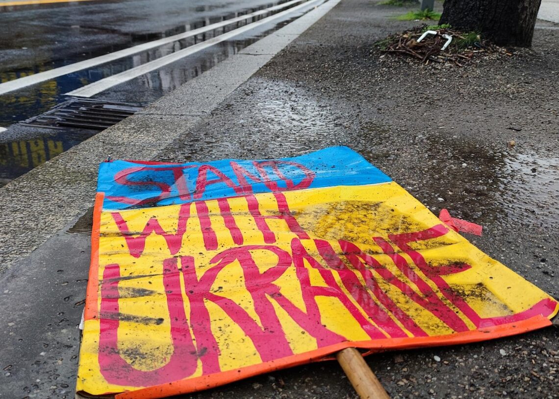 Schild `Stand with Ukraine` liegt auf dem Boden (Archiv)