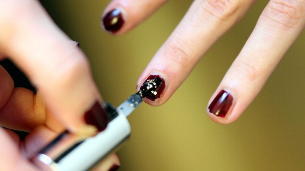 Frau lackiert Fingernägel mit Nagellack (Archiv)