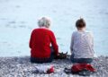 Alte und junge Frau sitzen am Strand