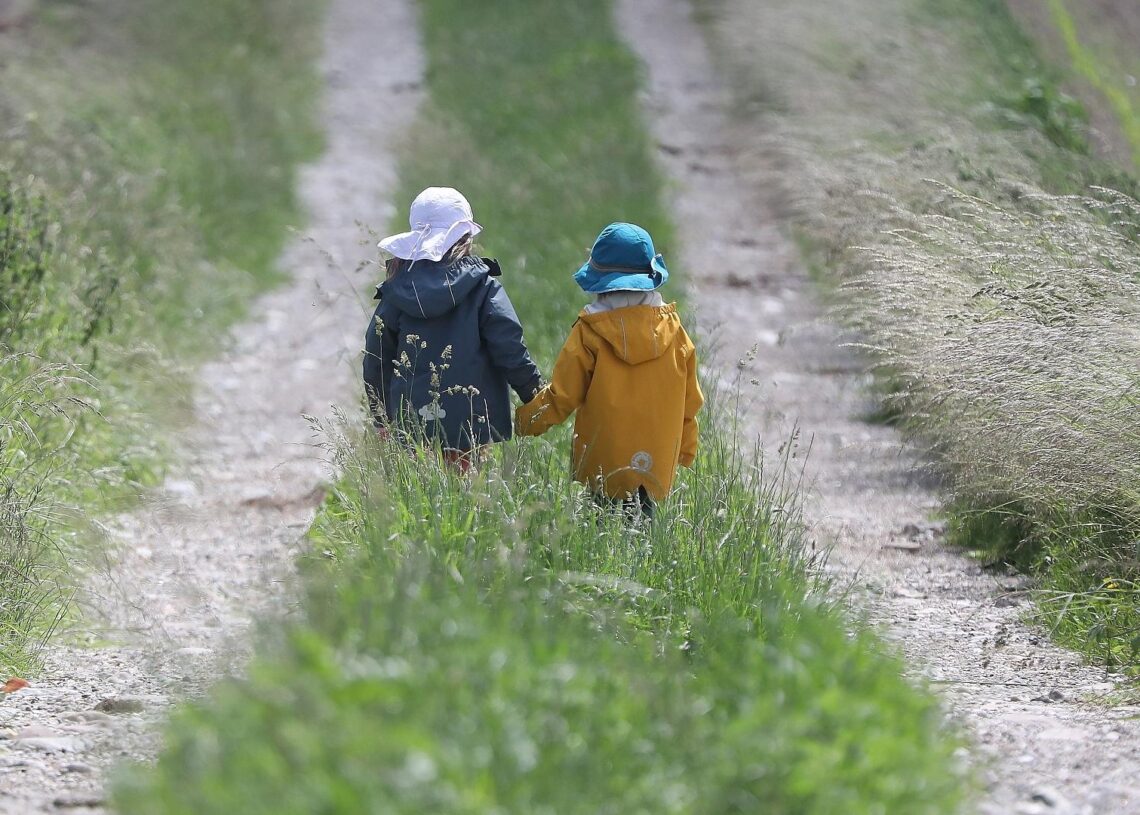 Zwei kleine Kinder laufen auf einem Feldweg (Archiv)
