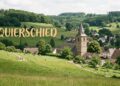Dorfansicht oder Landschaftspanorama der Gemeinde Quierschied mit grünen Wiesen und Waldrändern. Eventuell Kirchturm oder lokales Wahrzeichen im Mittelgrund. Der Schriftzug "QUIERSCHIED" in warmer, freundlicher Schrift, gut lesbar positioniert. Atmosphäre: Ländlich, gemeinschaftlich, naturverbunden.