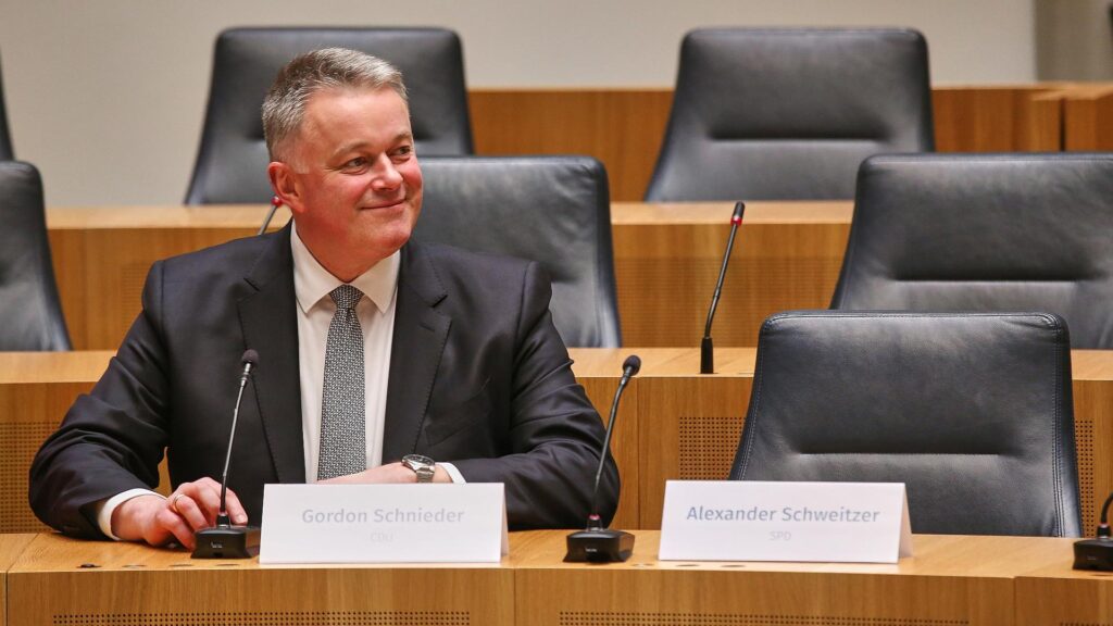 Gordon Schnieder sitzt neben dem leeren Stuhl von Alexander Schweitzer am 22.03.2026