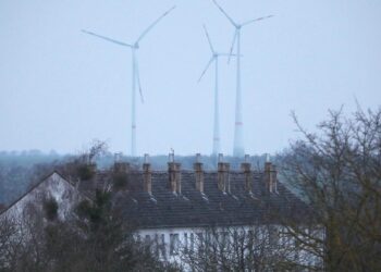 Ein Mehrfamilienhaus mit Windrädern im Hintergrund (Archiv)