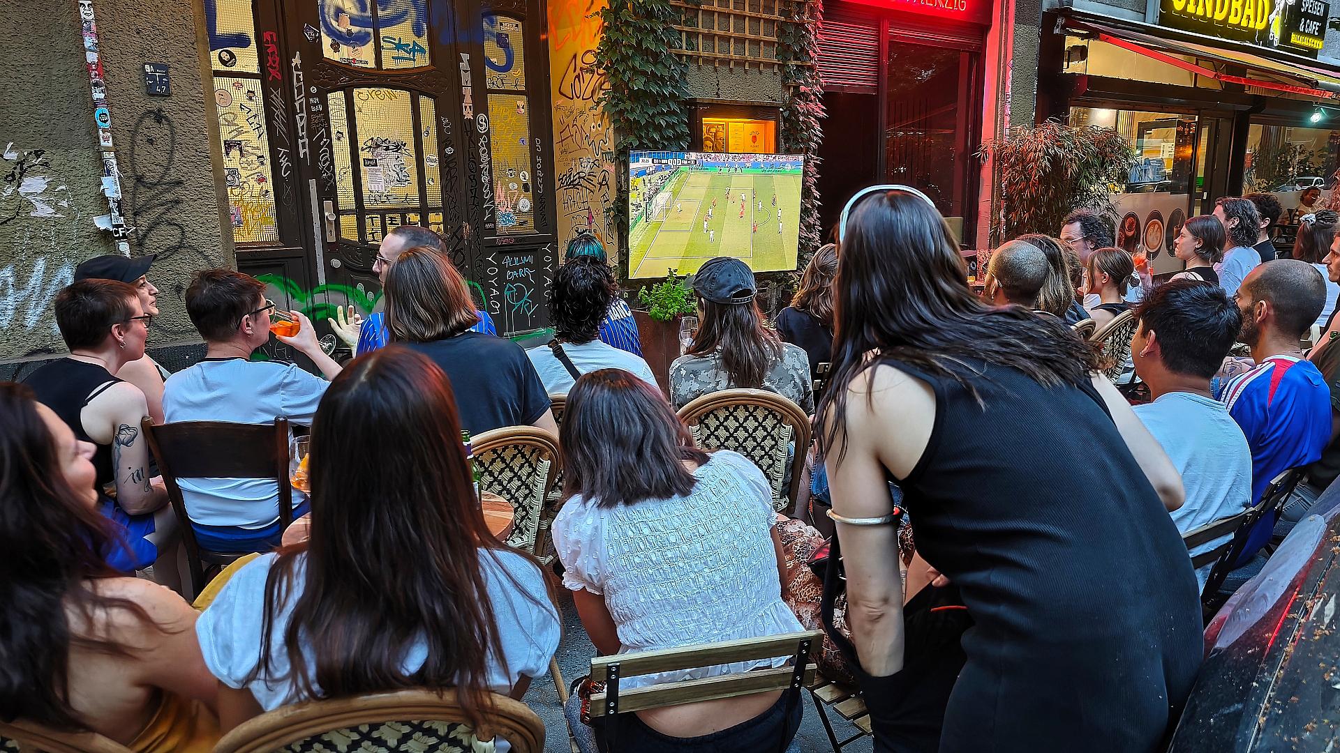 Interessierte schauen auf der Straße Fußball am 26.06.2026
